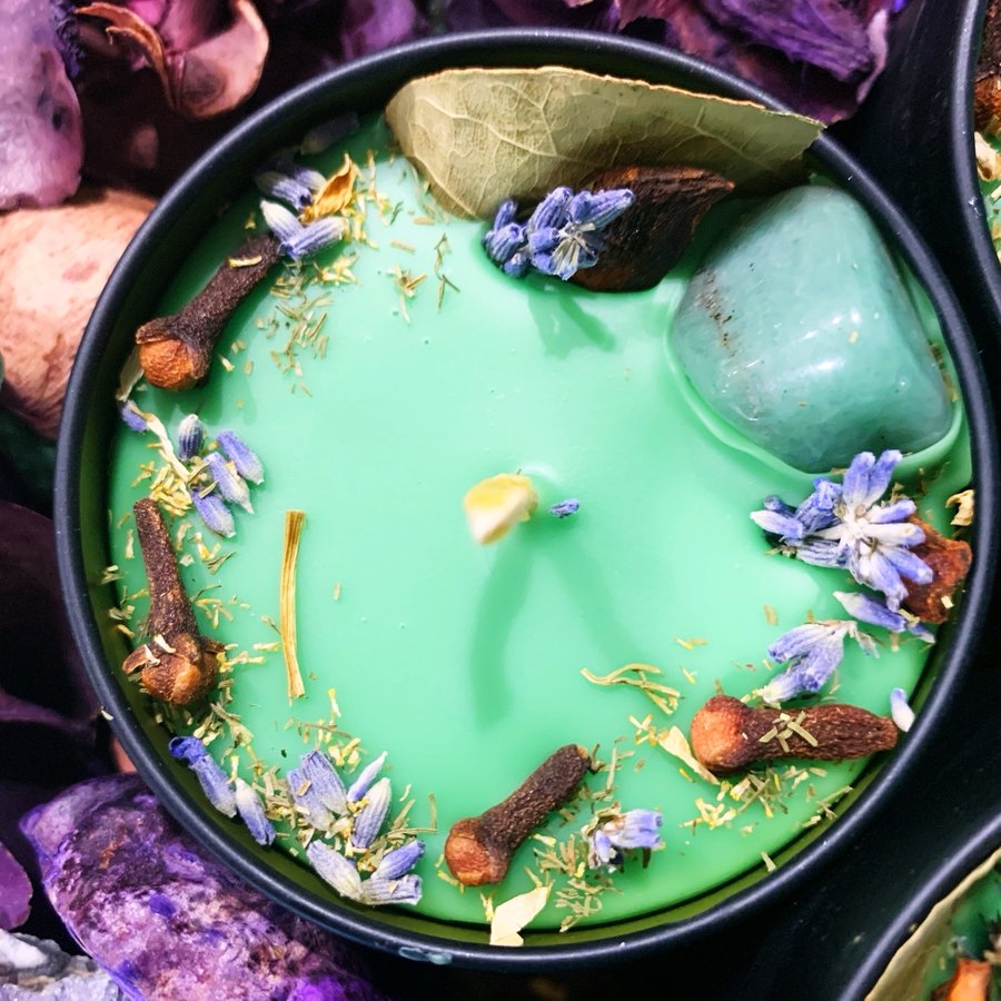 Green intention candle topped with cloves, lavender, a bay leaf and a green stone
