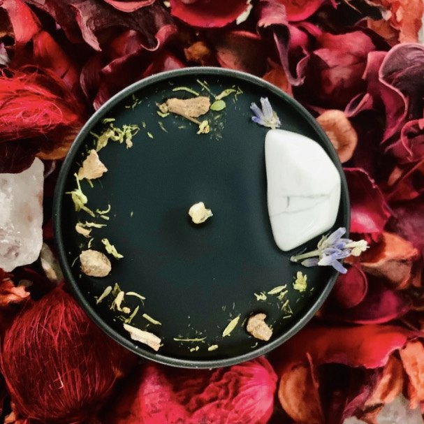 Black intention candle topped with lavender, botanicals and a white stone